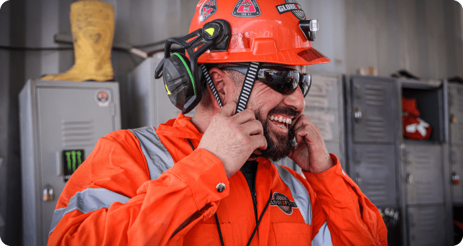 A joyful Globexplore worker dons a helmet with a laughter-filled smile, reflecting a positive and safety-conscious work environment.
