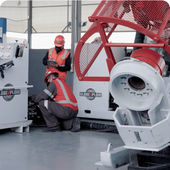 Dos trabajadores de Globexplore Drilling supervisando meticulosamente el rendimiento óptimo de unidades y maquinaria, ejemplificando su compromiso con la excelencia en operaciones de perforación.